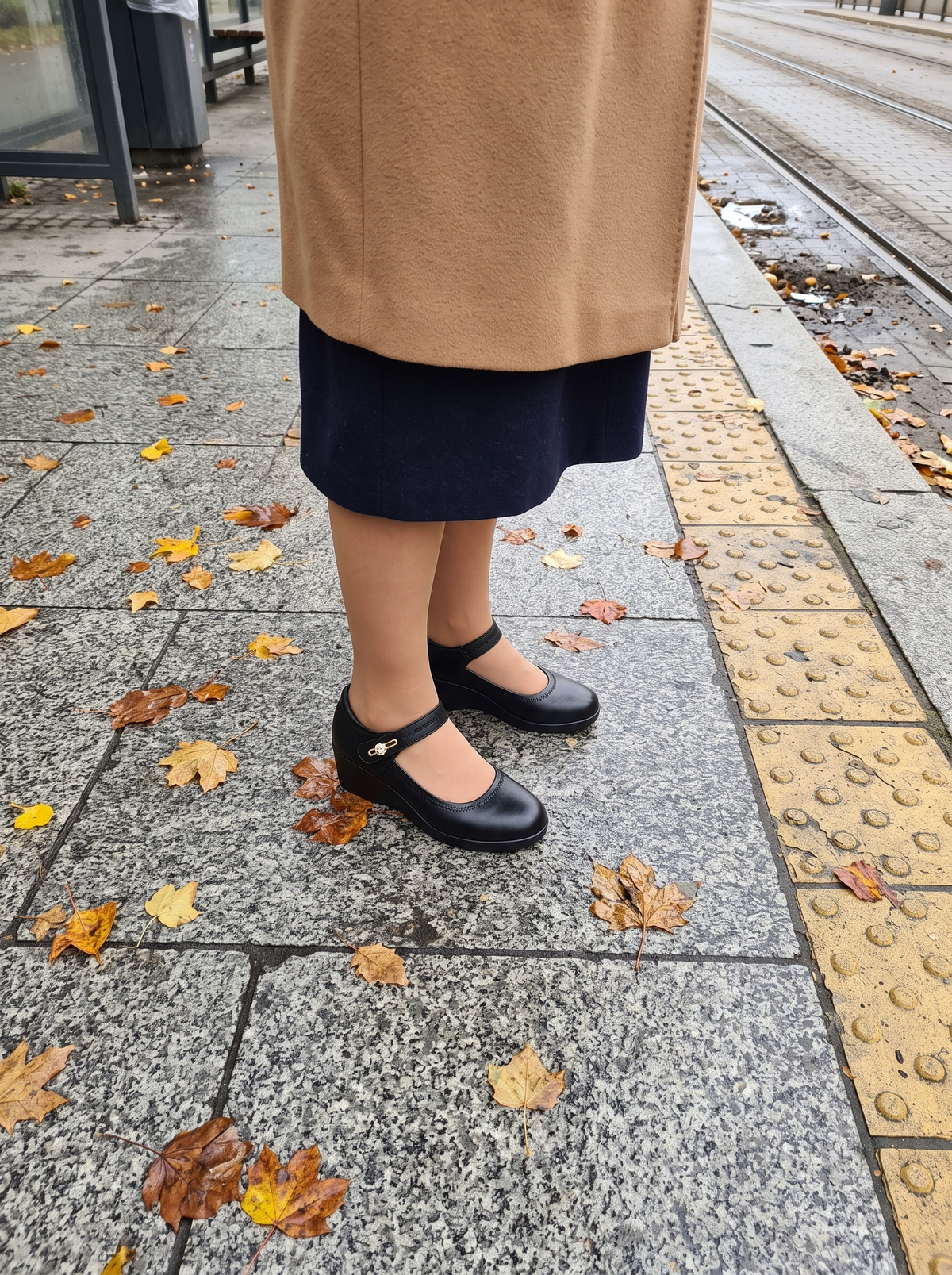 Czarne czółenka Danuta z paskiem na przystanku tramwajowym